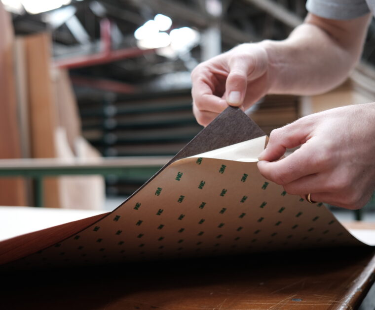 someone peeling the sticker off of a wood veneer sheet