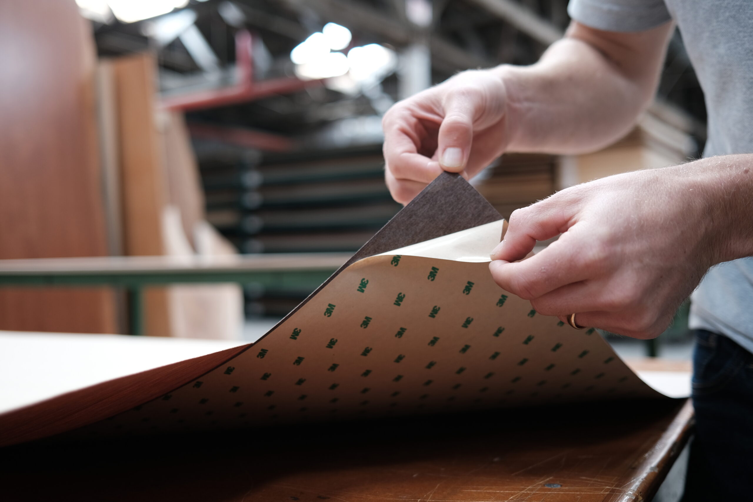 someone peeling the sticker off of a wood veneer sheet